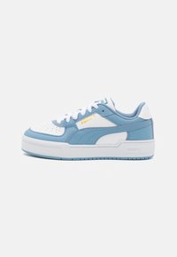 Lichtblauwe en witte sneaker met een getextureerde bovenkant, geperforeerde neus, gouden logo-accent en een stevige witte zool.