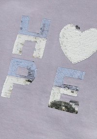 Un tessuto grigio presenta la parola "SPERANZA" in lettere di paillettes e un cuore di paillettes, con accenti blu e argento scintillanti.