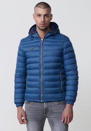 Chaqueta acolchada azul con diseño de acolchado, cremallera frontal, capucha y puños elásticos. Presenta un logo y dos bolsillos laterales con cremalleras.