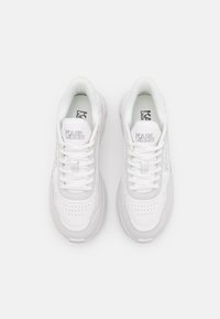 Weiße Sneaker aus glatten und strukturierten Materialien. Mit gepolstertem Kragen, perforierter Zehenpartie und dezentem Branding an der Seite und Zunge.