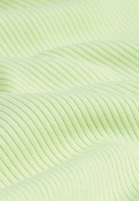 Gros plan sur un tissu côtelé vert clair montrant des lignes parallèles texturées et des plis doux.