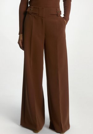 Bruine broek met hoge taille en brede pijpen, met zakken aan de zijkant en knoopsluitingen bij de taille, gecombineerd met een bijpassend geribd topje met lange mouwen.