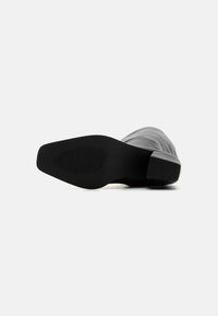 Zwarte rubberen laars zool met een gestructureerd grip patroon, voorzien van een slanke silhouet en een gladde, matte bovenkant.
