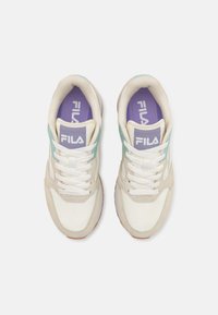 Zapatillas Fila con una parte superior de cuero blanco, acentos de gamuza beige, paneles laterales de color azul claro y una plantilla morada con el logo.