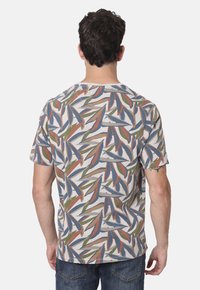 Camisa de manga corta para hombre, mezcla de algodón, con un patrón de hojas multicolores en tonos de verde, azul y óxido sobre un fondo claro.