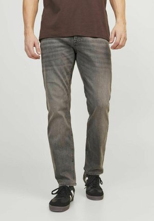 Graue Jeans mit geradem Schnitt, aus Denim gefertigt, mit subtilem Verblassen und kontrastierenden Nähten, kombiniert mit schwarzen Sneakern.