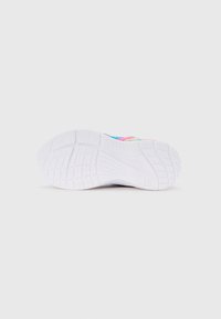 Suola in gomma bianca di una sneaker colorata che mostra un motivo testurizzato per la presa su uno sfondo chiaro e semplice.