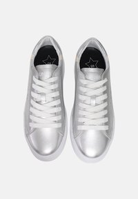 Sneaker argento con finitura metallizzata liscia. Presentano lacci bianchi, una soletta nera con un logo a stella e un design a punta arrotondata.