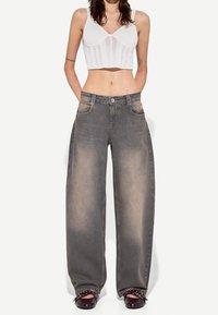 Vida vida, grå jeans med vida ben, som är urblekta, med två framfickor och knäppning, i kombination med en kort vit topp. Slät textur, avslappnad design.