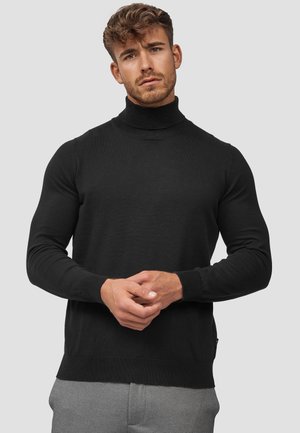Schwarzer Rollkragenpullover aus weichem Strickmaterial; mit langen Ärmeln und einem gerippten Saum, der eine taillierte Silhouette bietet.