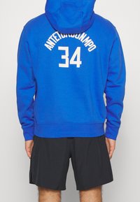 Sweat à capuche bleu roi avec cordon de serrage. Présente un texte blanc "ANTETOKOUNMPO" et le numéro "34" au dos. Coupe classique avec poignets et ourlet côtelés.