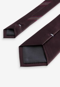 Bordo kravata od teksturirane tkanine, s dijagonalnim prugama u maroon, sivoj i smeđoj boji. Kvadratni završeci s crnim podstavom.