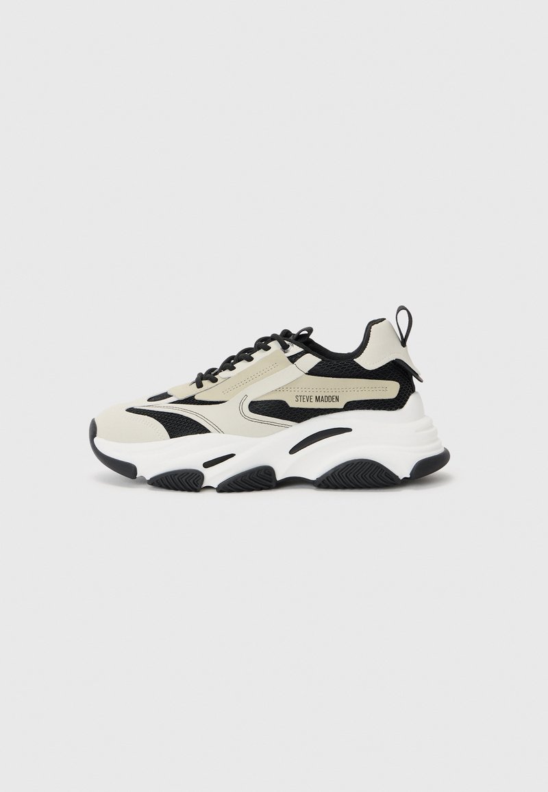 Chunky sneaker with a beige and black mesh upper, white midsole, black rubber outsole, and logo detailing on the side.