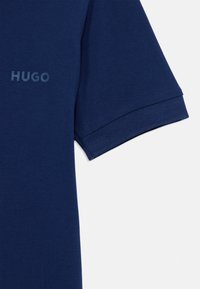 Jūrų laivyno polo marškiniai su tekstūruota medžiaga. Sukurtas su tekstūruota apykakle ir trumpomis rankovėmis. Krūtinėje matomas šviesesnio atspalvio "HUGO" logotipas.