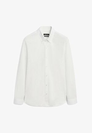 Chemise blanche à manches longues avec boutons, col à rabat et poignets boutonnés, présentée sur un fond blanc.