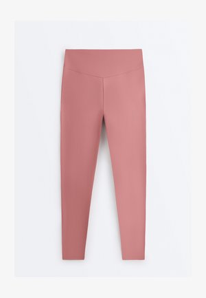 Højtaljede, tætsiddende leggings i mauve med glat stof uden synlige lommer eller mønstre, vist mod en ensfarvet hvid baggrund.