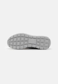 White rubber shoe sole with square and rectangular tread patterns, featuring rounded edges and grooves for grip.