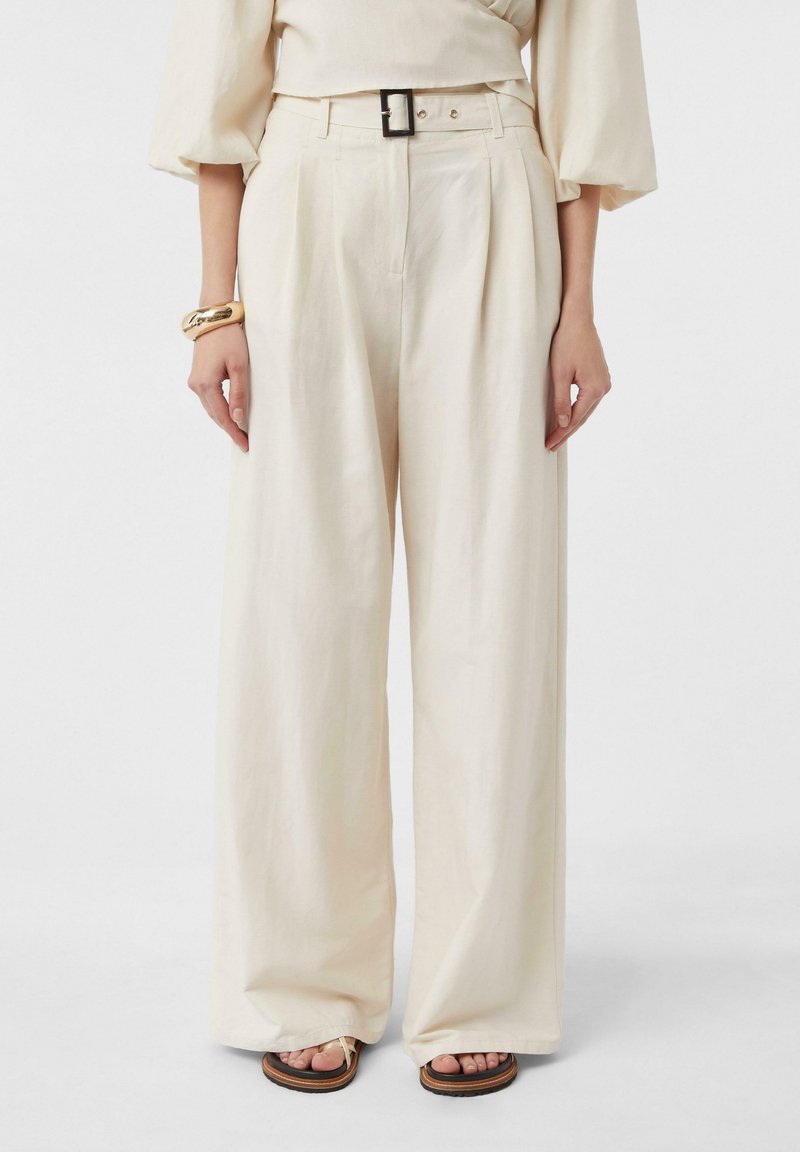Kremowe spodnie o szerokich nogawkach, wykonane z miękkiego materiału, z wysokim stanem, paskiem z prostokątną klamrą oraz plisowanym przodem.
