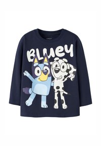 Marineblå genser med lange ermer laget av bomull, med en fargerik illustrasjon av to tegnefilmhunder, en blå og en med flekker, med teksten "BLUEY".