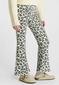 Uitlopende broek met luipaardprint van zachte stof, met een witte achtergrond en zwarte en bruine vlekken, gecombineerd met beige instappers.