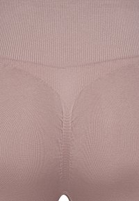 Seamless shapewear in a light brown color with ribbed texture. Features a smooth finish and a subtle high-waisted design.