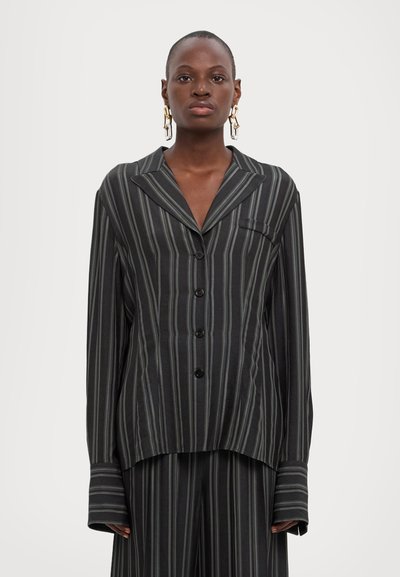 Black and gray striped long-sleeve shirt with large collar, chest pocket, and button closure. Loose fit with wide cuffs.