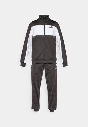 Zwart-wit trainingspak met een ritsjack dat een witte horizontale streep en geribde manchetten heeft, in combinatie met bijpassende zwarte broeken.