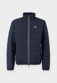 Μπλε μπουφάν με καπιτονέ σχέδιο, φερμουάρ μπροστά, όρθιο γιακά, ελαστικά μανίκια και μικρό λογότυπο EA7 στο στήθος.