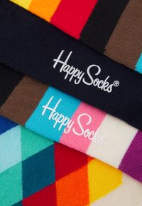 Šarene pamučne čarape s različitim geometrijskim uzorcima i trakama. Oznake prikazuju "Happy Socks" u bijeloj boji na tamnim pozadinama.