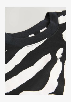 Tricou negru cu un model îndrăzneț de dungi albe în stil zebra, guler rotund, mâneci scurte și textură moale din bumbac.