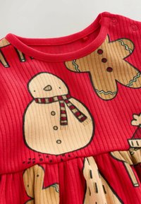 Rotes geripptes Kleid mit Schneemann- und Lebkuchenmustern, ergänzt durch gelbe Akzente. Mit Druckknöpfen an der Schulter für ein einfaches An- und Ausziehen.