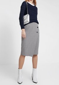 Granatowy prążkowany top z długim rękawem, szara spódnica ołówkowa w checkered z guzikami, zestawiona z białymi botkami do kostek i białą torbą z metalowymi akcentami.