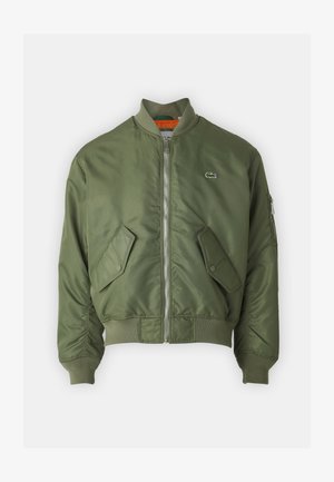Giubbotto bomber verde oliva con zip frontale, polsini a coste e due tasche frontali. Presenta un piccolo logo sul lato sinistro del petto e una fodera interna a contrasto.