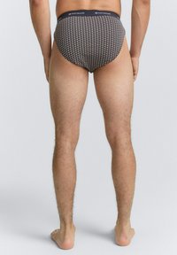 Zwarte patronen onderbroek met een marineblauwe elastische tailleband. Kenmerkend is het geometrische ontwerp met stippen en vormen. Zachte stofstructuur, aansluitende pasvorm.