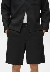 Shorts noirs en tissu léger, avec une coupe droite, des poches latérales et une taille avec bouton. Design minimaliste.