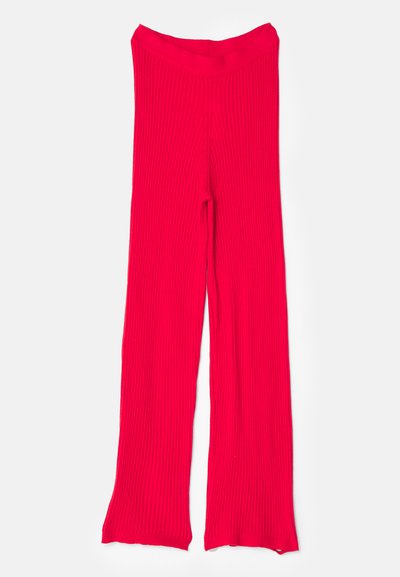 Pantalons en tricot rouge à côtes avec une taille haute, une jambe évasée et une texture lisse. Le tissu présente des lignes verticales sur toute sa surface.