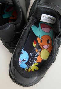 Baskets noires avec un extérieur en cuir texturé. La doublure intérieure présente des personnages Pokémon colorés, y compris Squirtle, Salamèche et Pikachu.