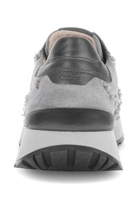 Grijze suède sneaker met een zwarte leren hiel, witte zool en textuurpatronen op de bovenkant. Heeft een merkaccent op de hiel.