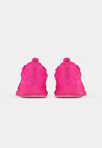 Pink athletic shoes with a textured upper, rear pull tabs, and visible cushioning. Features "TRAINING" embossed on the heel.