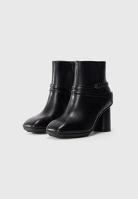 Black leather ankle boots with a rounded toe, featuring a side zipper, a strap detail, and a chunky heel. Smooth texture with a polished finish.