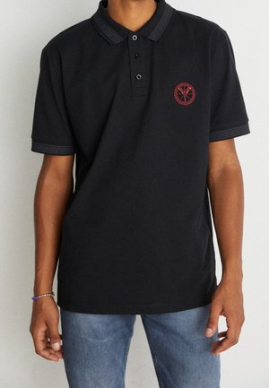 Zwarte polo met decoratieve kraag en drie knopen. Voorzien van een rood geborduurd logo en een gestreepte afwerking op de mouwen. Casual pasvorm.