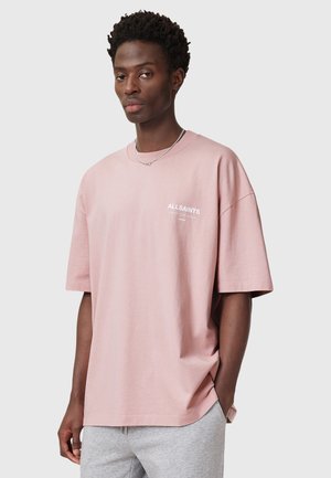 Overdimensioneret blush pink t-shirt lavet af bomuld med korte ærmer og rund halsudskæring; har et lille hvidt logo på brystet.