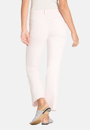 Woman wearing light pink cropped jeans with raw hem and silver slip-on shoes, shown from back against white background.