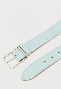 Φως μπλε σουέντ ζώνη με ασημί μεταλλική αγκράφα και ραφές πάνω σε λευκό φόντο.