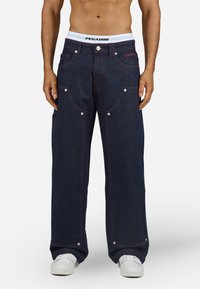 Dark blue denim trousers with a wide leg cut, featuring red stitching, multiple pockets, and metal snap accents. Includes a white waistband.