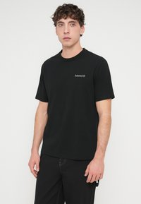 Μαύρο βαμβακερό t-shirt με στρογγυλή λαιμόκοψη και κοντά μανίκια, με ένα μικρό, ανάγλυφο λογότυπο Timberland στο αριστερό στήθος.