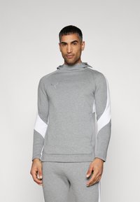 Grå sports sweatshirt med høj krave, hvide sideaccenter og hætte, lavet af et glat og strækbart stof. Har en forlommer.