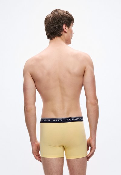 Žlté bavlnené boxerky s tmavomodrým elastickým pásom s logom "POLO RALPH LAUREN", pohľad zozadu.