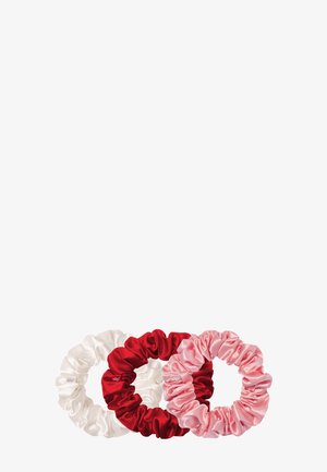 Trois chouchous en satin en blanc, rouge et rose clair, présentant une texture lisse et un design froncé pour coiffer les cheveux.