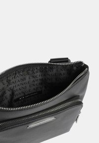 Borsa in pelle nera con chiusura con zip, esterno texturizzato e fodera con logo in rilievo. Include una tasca zip aggiuntiva.